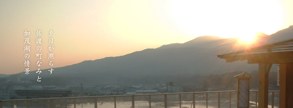 夕日が照らす佐渡の町なみと加茂湖の情景